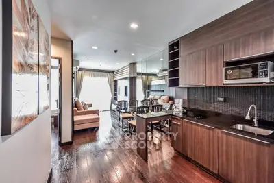 Modern open-layout kitchen and living room with wooden flooring and stylish decor.