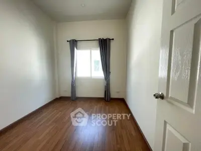 Spacious empty room with wooden flooring and natural light, perfect for customization.