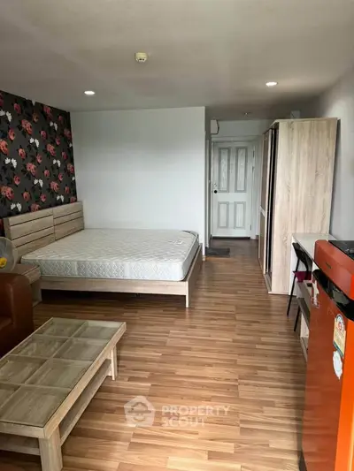 Spacious studio apartment with modern decor and wooden flooring, featuring a cozy bed and stylish furniture.