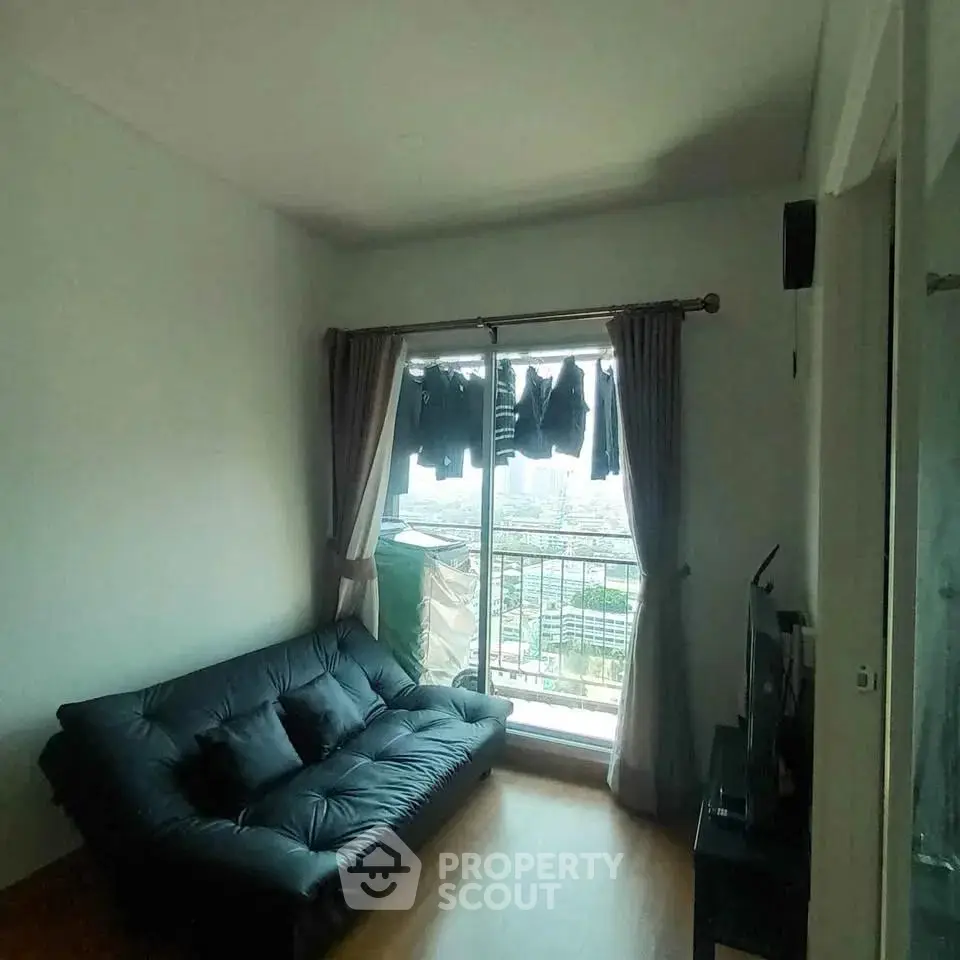 Cozy living room with a black sofa and city view from the window, perfect for urban living.