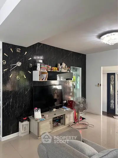 Modern living room with large wall clock and sleek black marble accent wall.