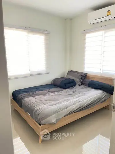 Cozy bedroom with natural light and modern decor, featuring a comfortable bed and air conditioning.