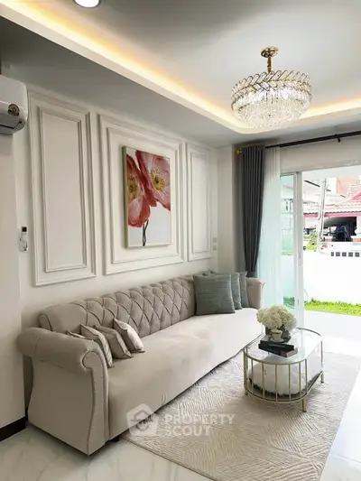 Elegant living room with plush sofa, chandelier, and garden view through glass doors.