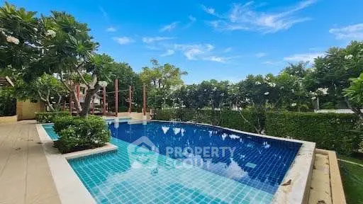 Luxurious outdoor pool surrounded by lush greenery and clear blue skies, perfect for relaxation and leisure.