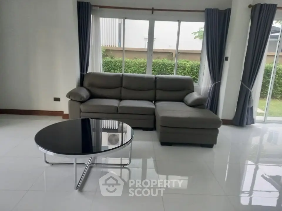 Spacious living room with modern sofa and garden view, perfect for relaxation.