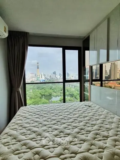 Modern bedroom with stunning city view from large window, featuring elegant decor and natural light.