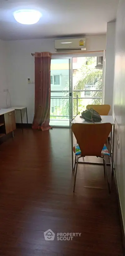 Bright living room with wooden flooring and balcony access in modern apartment.
