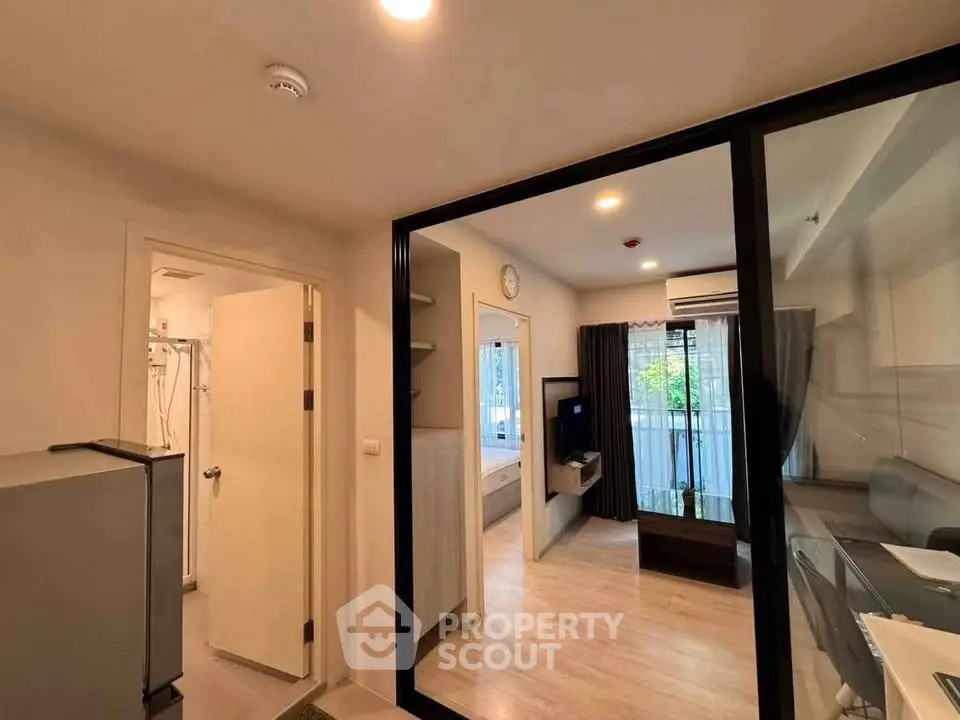 Modern apartment interior with glass partition, cozy living area, and natural light.