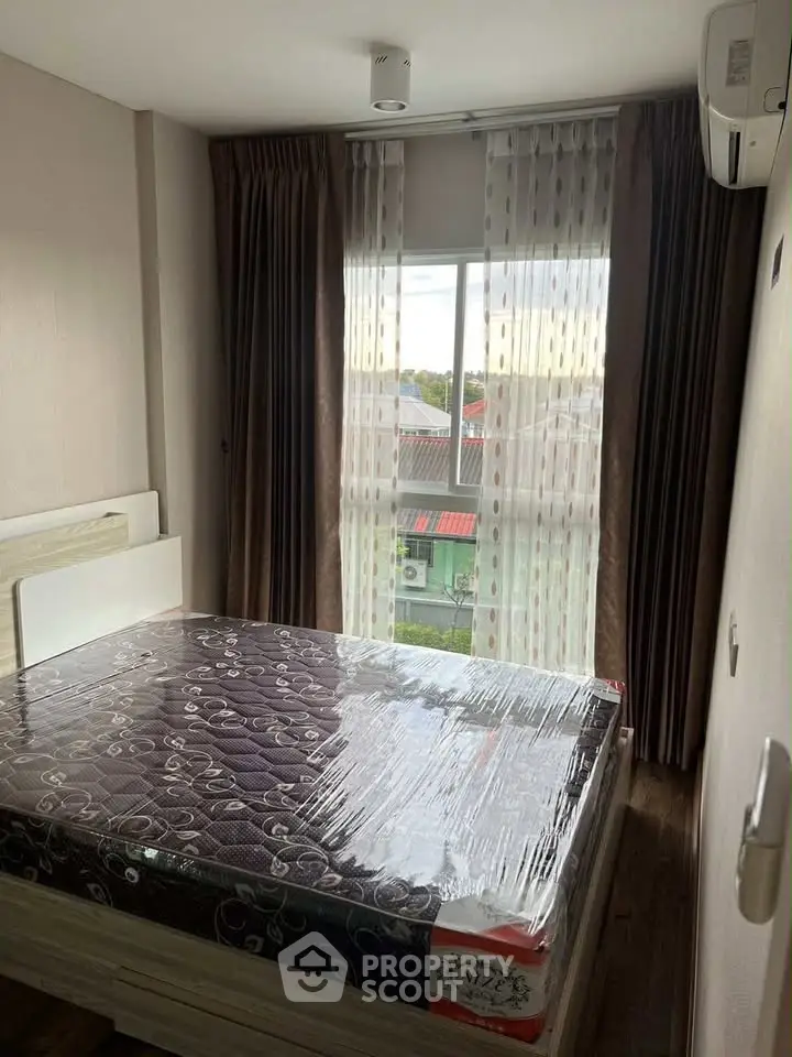 Cozy bedroom with large window and modern furnishings in a stylish apartment.