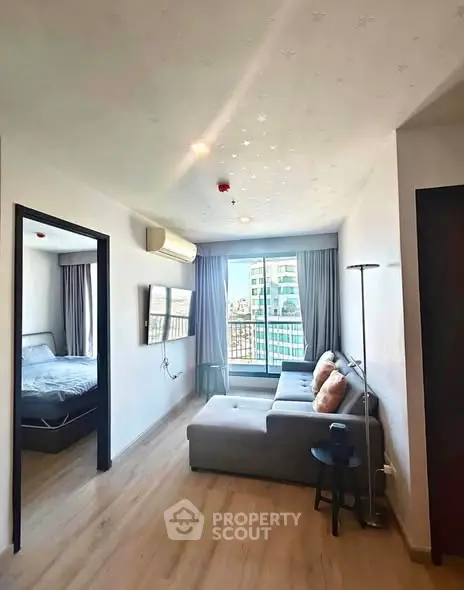 Modern living room with cozy sofa and city view, adjacent to a stylish bedroom.