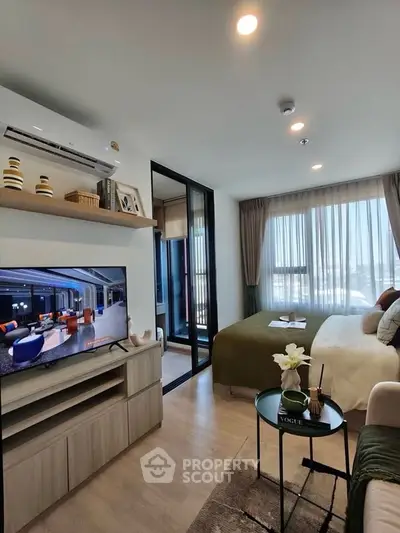 Modern bedroom with stylish decor and natural light, featuring a cozy bed and entertainment area.