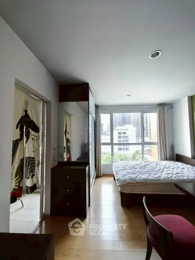 Spacious bedroom with large window and city view, featuring modern decor and ample natural light.