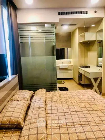 Modern bedroom with ensuite bathroom featuring glass partition and stylish decor.