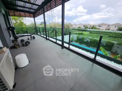 Spacious balcony with modern glass railing and lush garden view