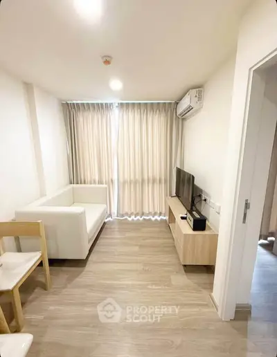 Modern living room with sleek furniture and natural light, featuring a cozy sofa and entertainment unit.