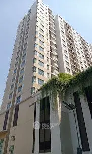 Modern high-rise building with lush greenery and clear blue sky