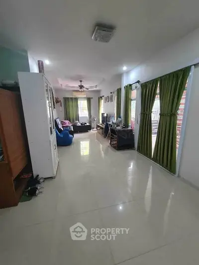 Spacious living room with green curtains and modern furnishings, perfect for family gatherings.