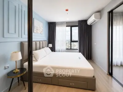 Modern bedroom with large window and city view, featuring stylish decor and ample natural light.