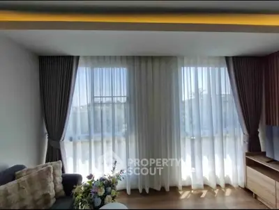 Bright and cozy living room with large windows and elegant curtains, perfect for relaxation.