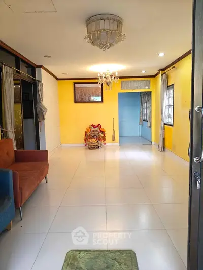 Spacious living room with vibrant yellow walls and elegant chandelier, perfect for family gatherings.