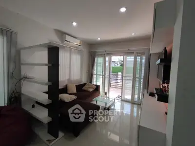Modern living room with sleek furniture and large windows opening to a balcony.