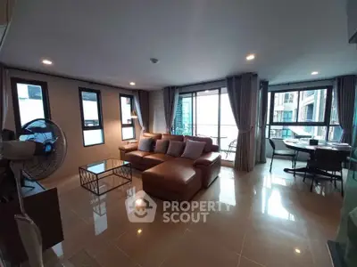 Spacious modern living room with large windows and stylish furniture in a high-rise apartment.