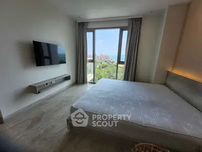 Spacious bedroom with large window offering stunning views of lush greenery and distant buildings.