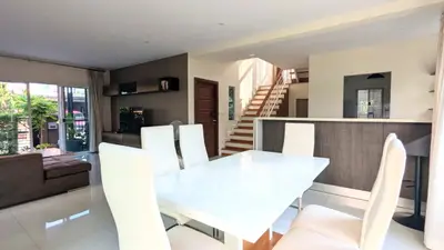 Spacious modern living room with elegant dining area and staircase in a bright open layout.
