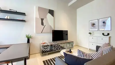 Modern living room with stylish decor, featuring a sleek TV stand, abstract art, and cozy seating area.