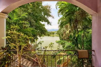 Tropical balcony view overlooking lush greenery and serene lake, perfect for relaxation and nature lovers.