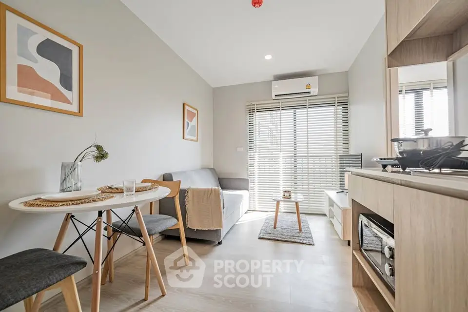 Modern living room with stylish decor and natural light, featuring a cozy dining area and sleek furnishings.