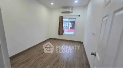 Spacious empty bedroom with wooden flooring and air conditioning