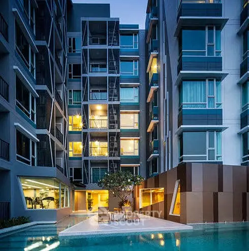 Modern apartment building with illuminated windows and inviting pool area at dusk.