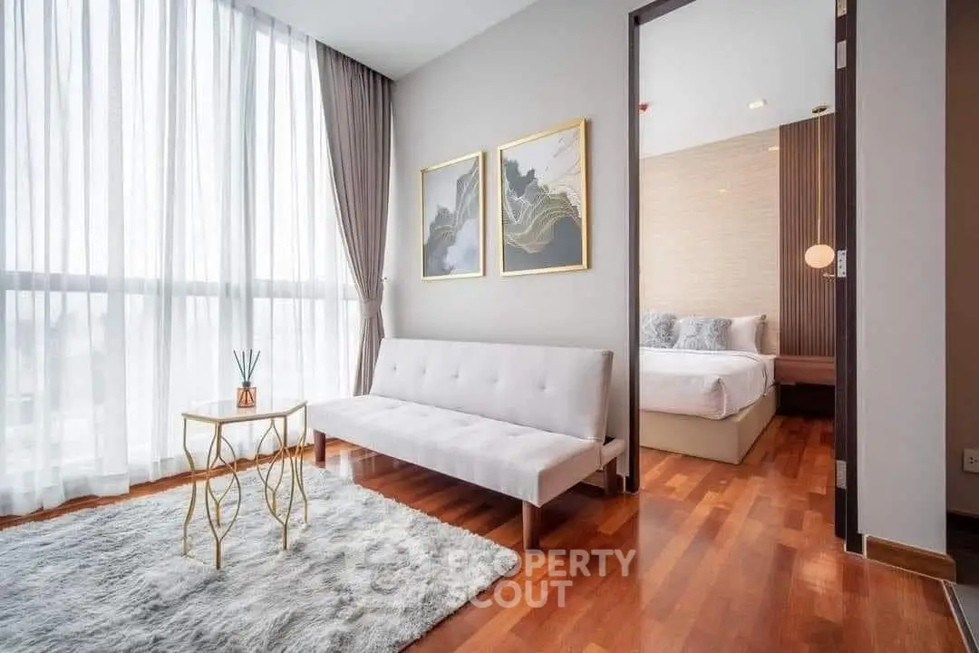 Stylish modern living room with elegant decor and natural light, adjacent to a cozy bedroom.