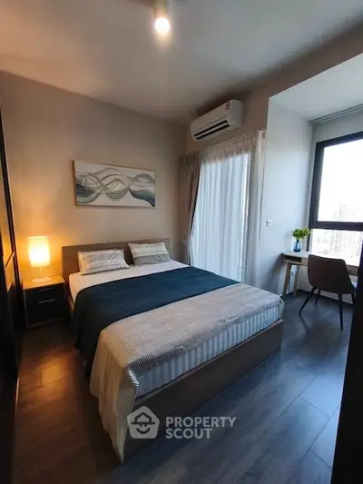 Modern bedroom with stylish decor, large window, and cozy ambiance in a high-rise apartment.