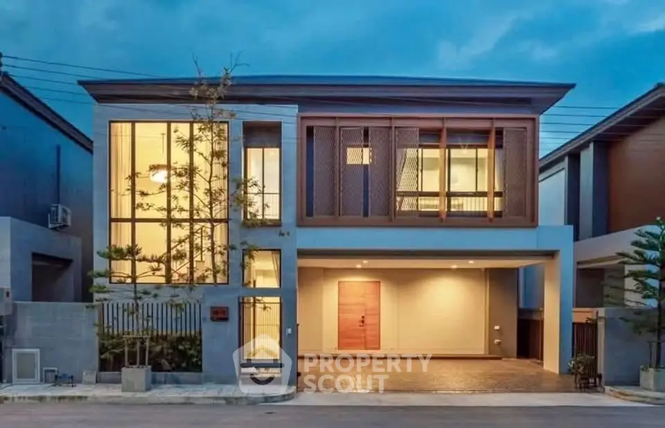 Modern two-story house with large windows and stylish facade under a twilight sky.