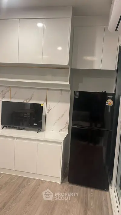 Modern kitchen with sleek cabinetry and black refrigerator in a stylish apartment.