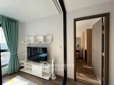 Modern living room with TV and stylish shelving, featuring a glimpse into a cozy bedroom.