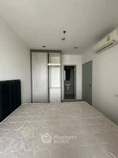 Modern bedroom with ensuite bathroom and air conditioning in a minimalist apartment.