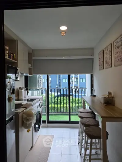 Modern kitchen with balcony view, featuring sleek appliances and stylish bar seating.