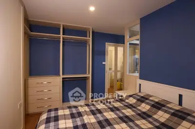Spacious bedroom with built-in closet and modern blue accent wall.