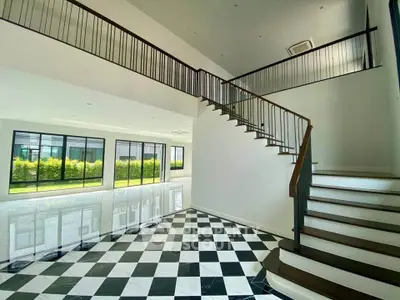 Spacious modern interior with elegant staircase and large windows overlooking greenery.
