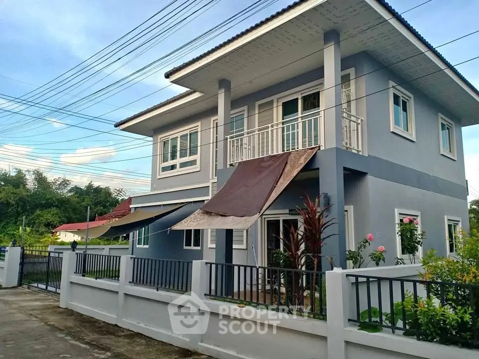 Modern two-story house with balcony and garden in a serene neighborhood.