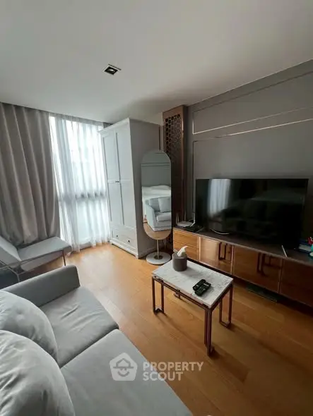 Modern living room with sleek furniture and large TV, featuring elegant decor and natural light.