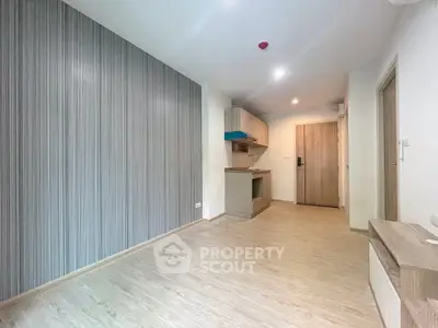 Modern minimalist apartment interior with wood flooring and compact kitchen area.