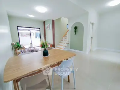 Spacious modern living room with dining area and staircase, featuring elegant decor and natural light.