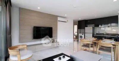 Modern open-plan living room with sleek kitchen and dining area, featuring stylish furniture and appliances.