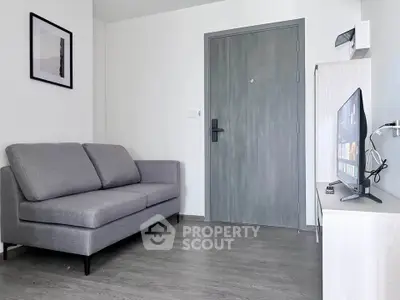Modern living room with sleek gray sofa and wall-mounted TV, perfect for cozy relaxation.