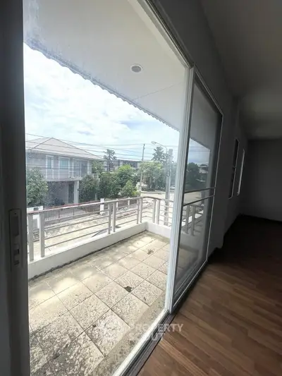 Spacious balcony with sliding glass doors offering a serene view of the neighborhood.