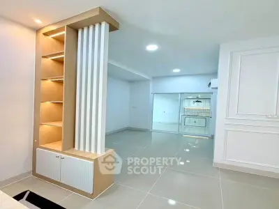 Modern open-plan living area with sleek built-in shelving and glossy tiled floors.